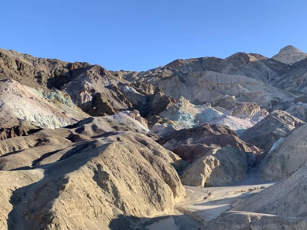 朝日の下でピンク、エメラルドグリーンや青に輝く砂漠の山々。