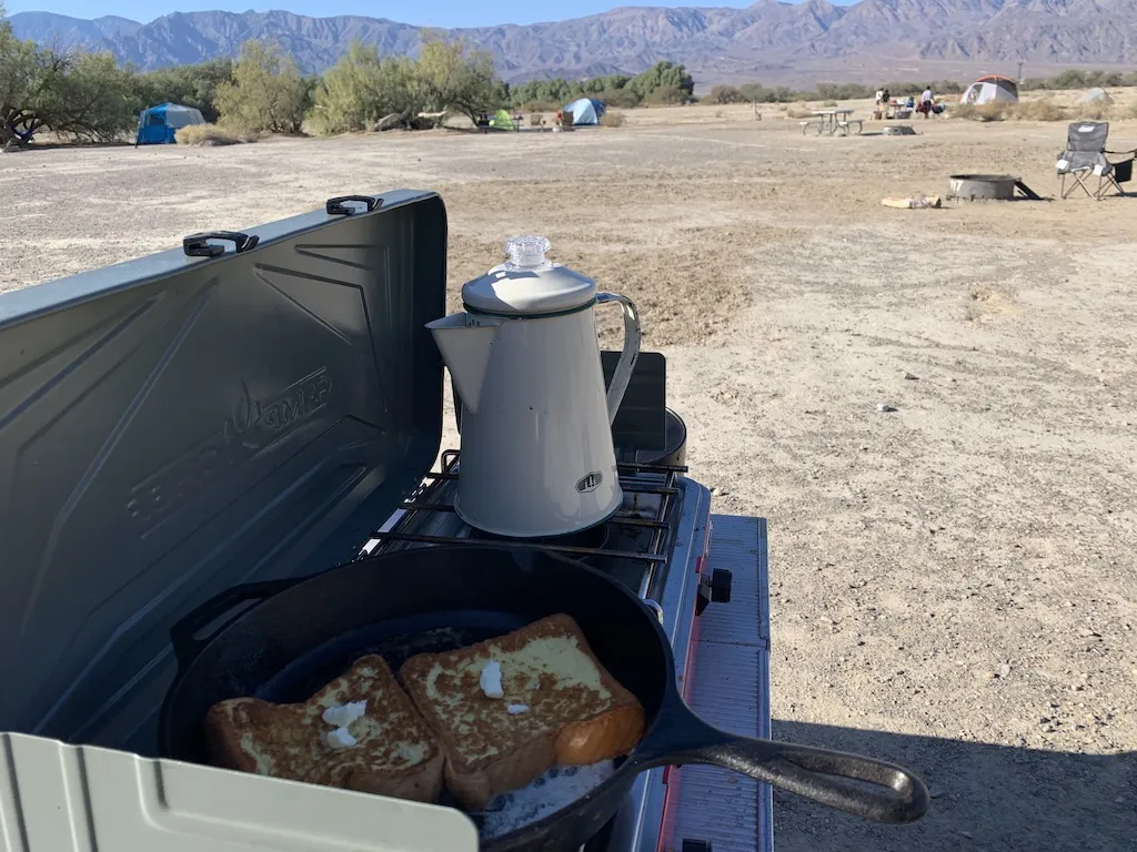 ファーニスクリークキャンプ場のキャンプサイトをバックにフレンチトーストが焼かれているフラインパンとやかん。