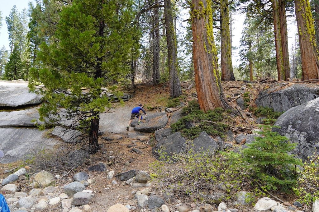 A boy is going up on the unpaved hill.