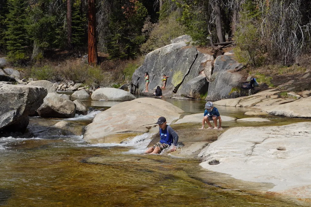 Two boys are sliding on the natural rocks at Dinkey Creek.
