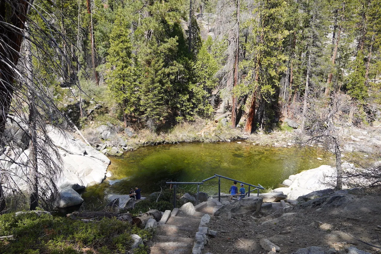 Two little kids are looking at a natural pool.