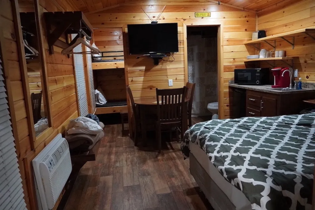 A queen sized bed and a bunkbed in the back inside the cabin.