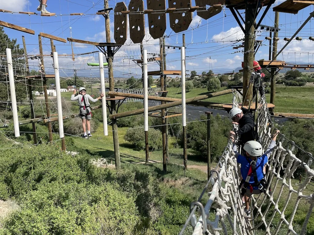 Dad and a boy are walking on the net at rope course by Arkansas river at Browns Canyon Adventure Park in Colorado.