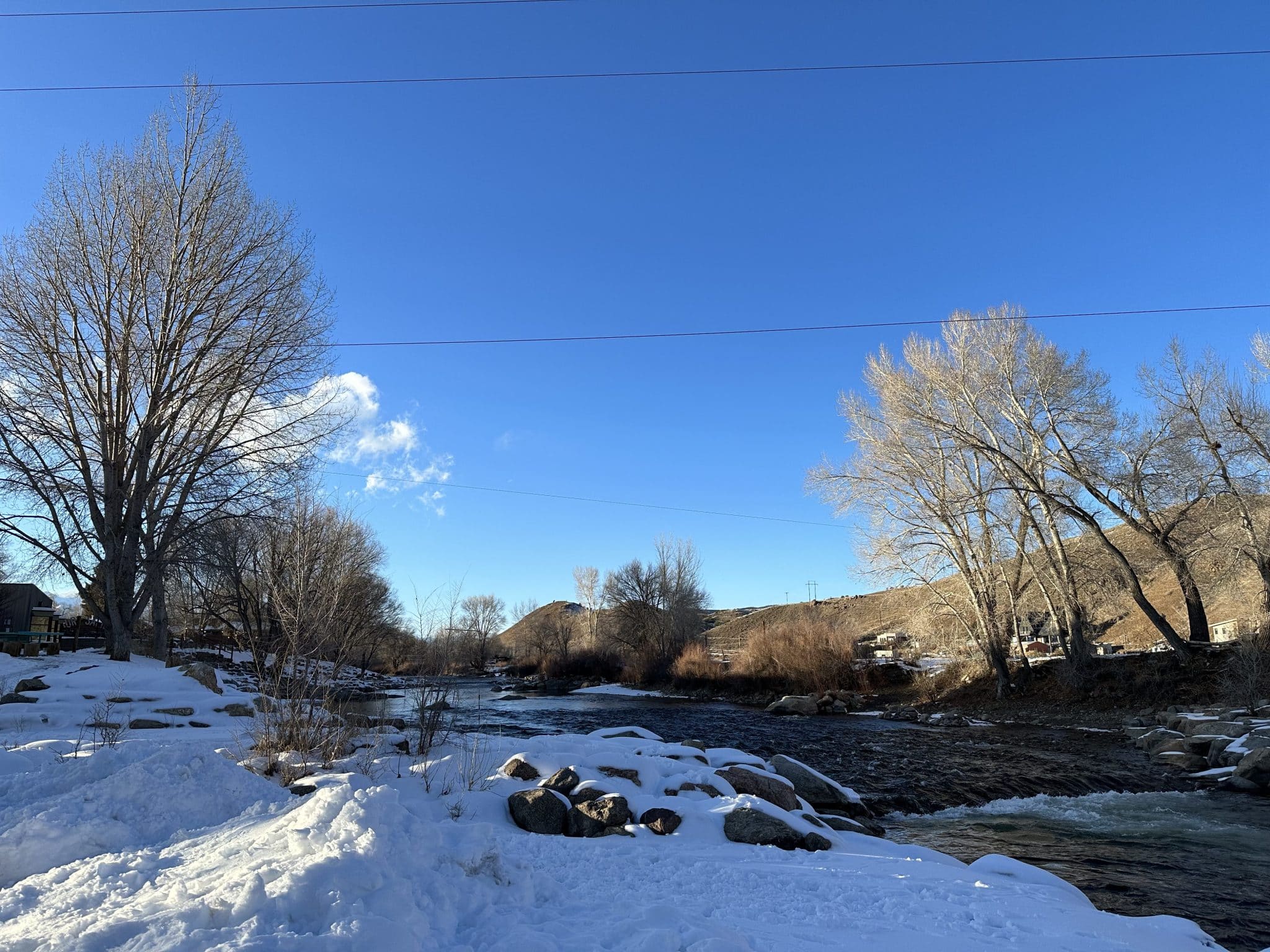 White river and snow covered shore in Riverside Park in Salida, Colorado.