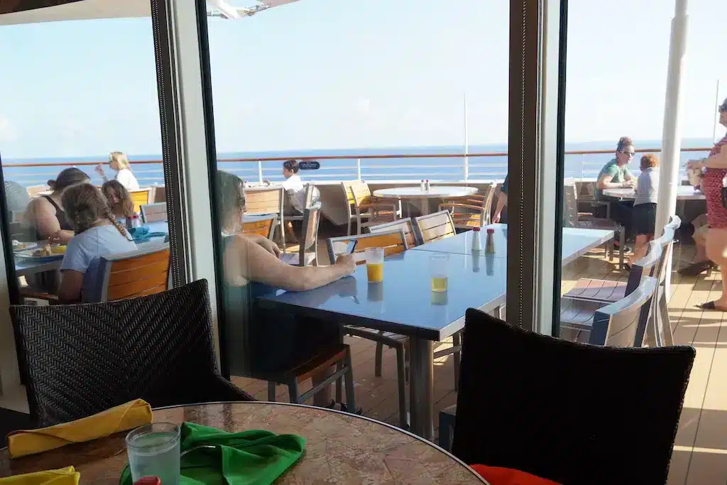 people eating at the Disney restaurant both indoors and outdoors on the back of the ship looking out at the ocean