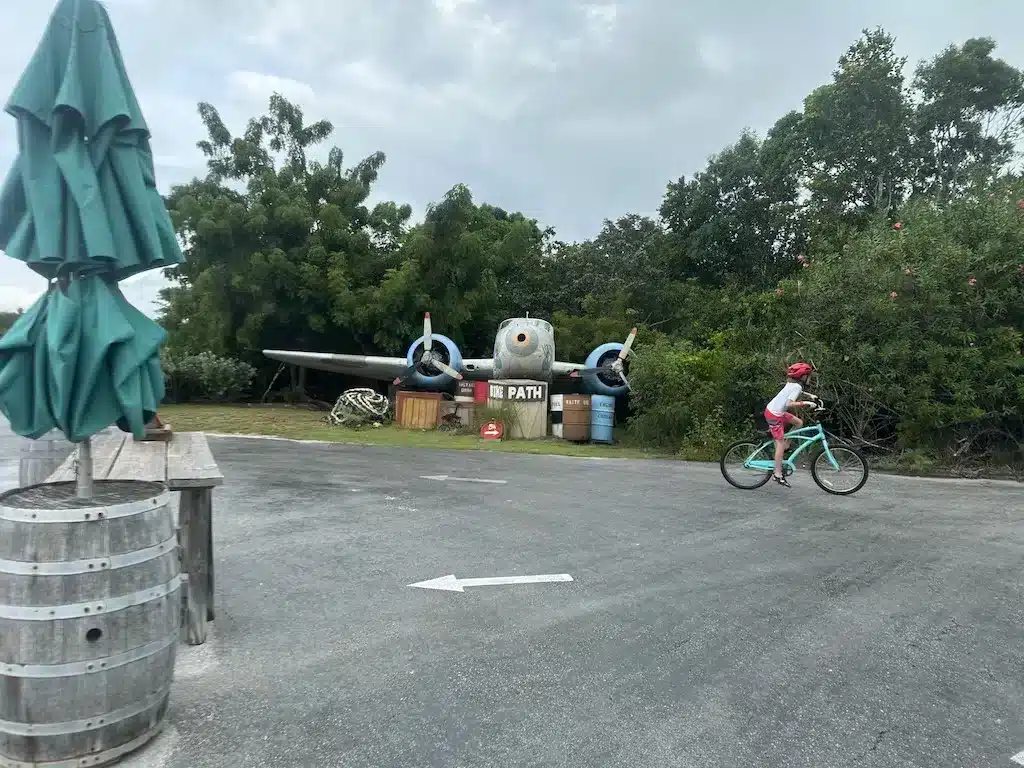 A boy riding a emerald bike passing the airplane decoration.