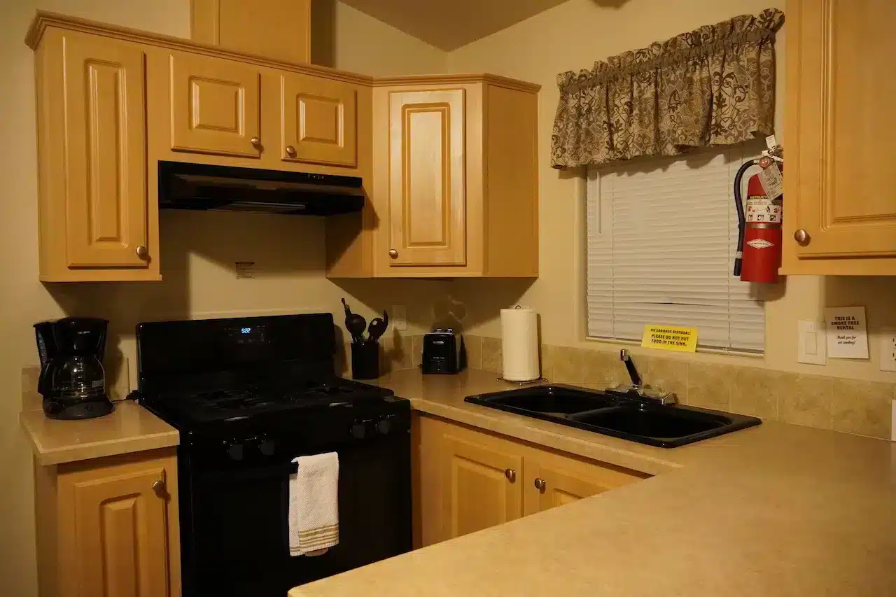 コンロやシンク、コーヒーメーカー付きのKOAキャビンのキッチン。木製キャビネットが備わった快適なファミリー向けのグランピング設備