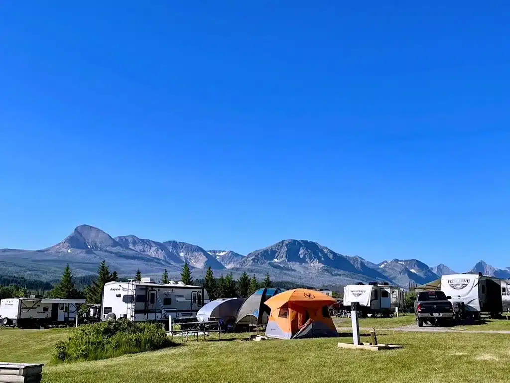 Scenic KOA campground with RVs and tents set up against a backdrop of mountains and blue sky — ideal for nature lovers and outdoor family camping.