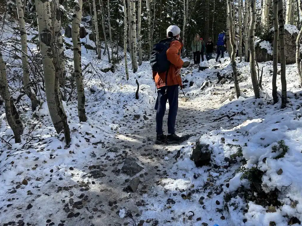 A boy walking on snow covered and icy trail in Maroon Bells.