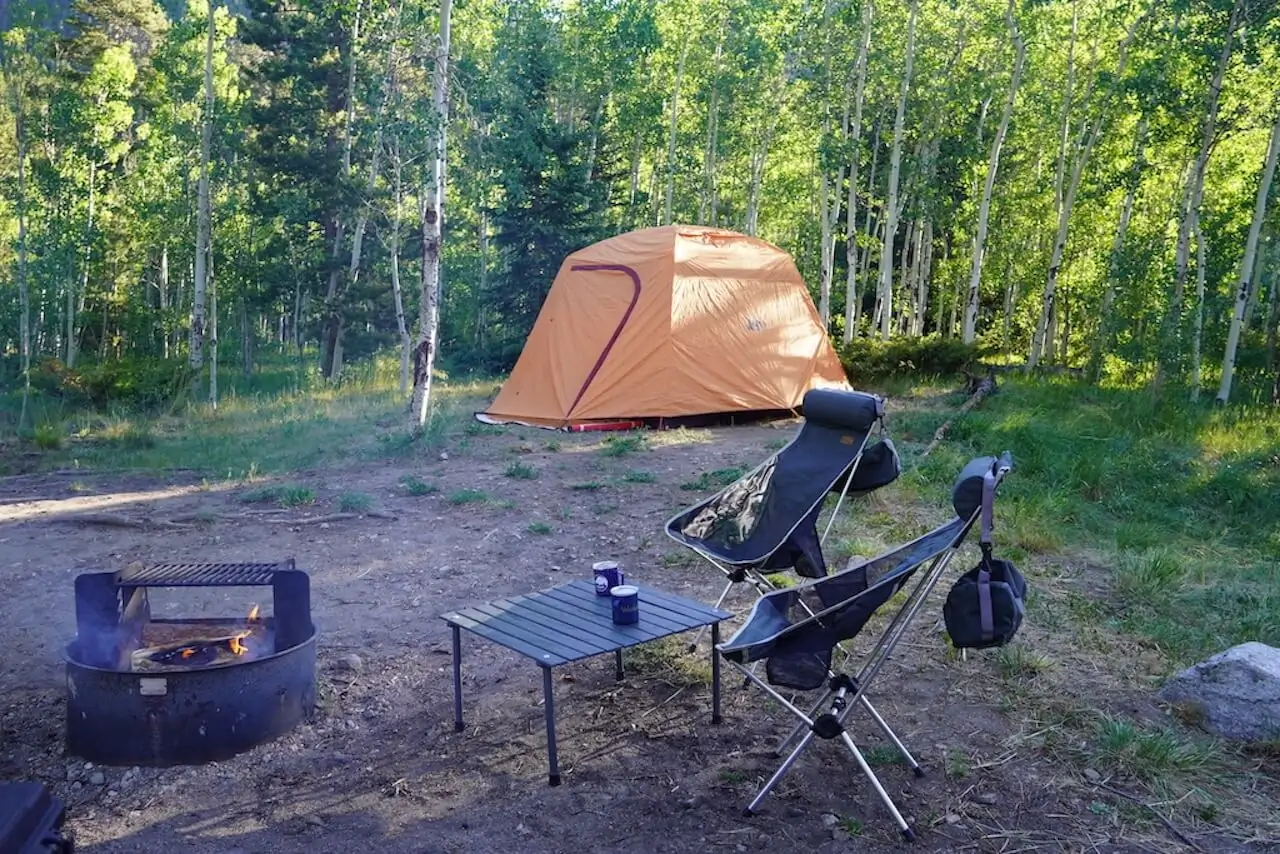 A orange tent, two camping chairs and mini table are located by a fire ring at Collegiate Peaks Campground in Colorado.