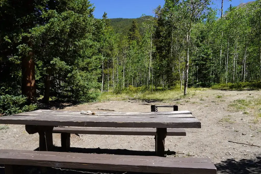 Old wooden picnic table and benches at a campsite of Collegiate Peaks Campground in Colorado.