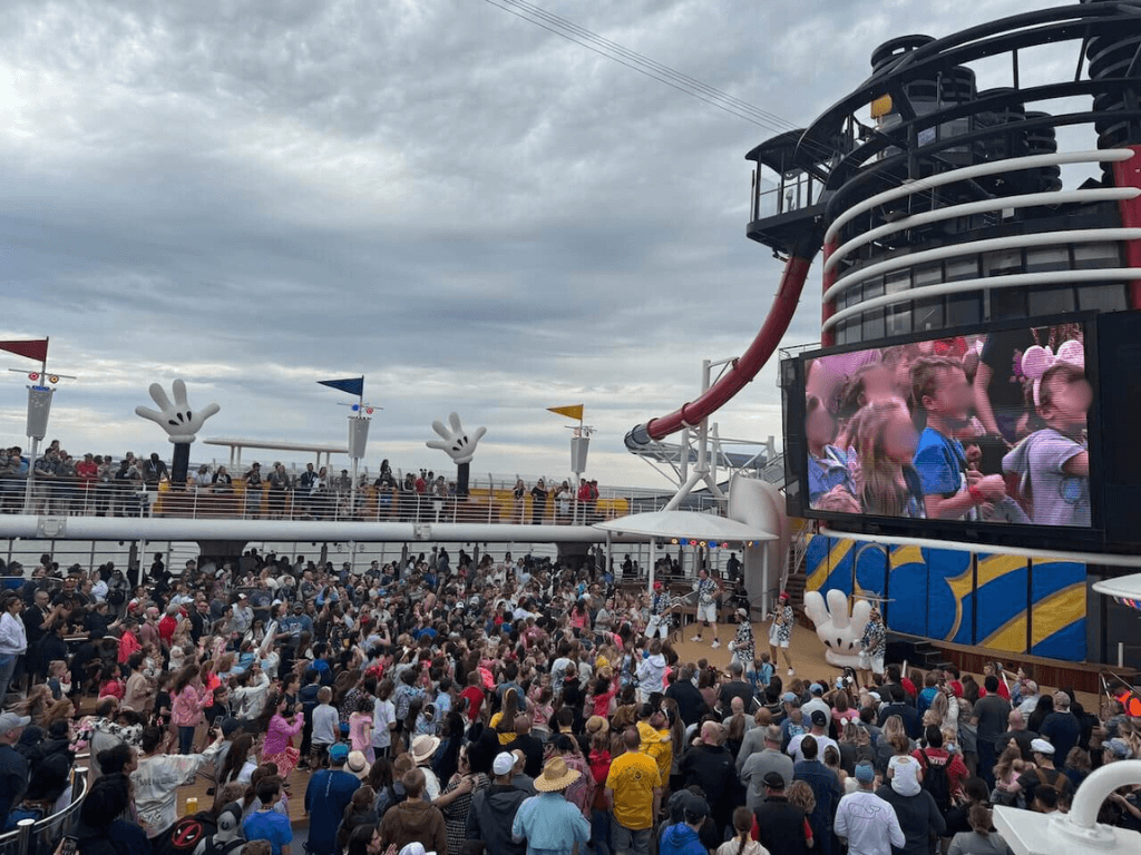 DCL_Sail Away Party - Tomo Travel & Camping People are standing up and getting ready for Disney Cruise Sail Away Celebration Party on the top of the deck.