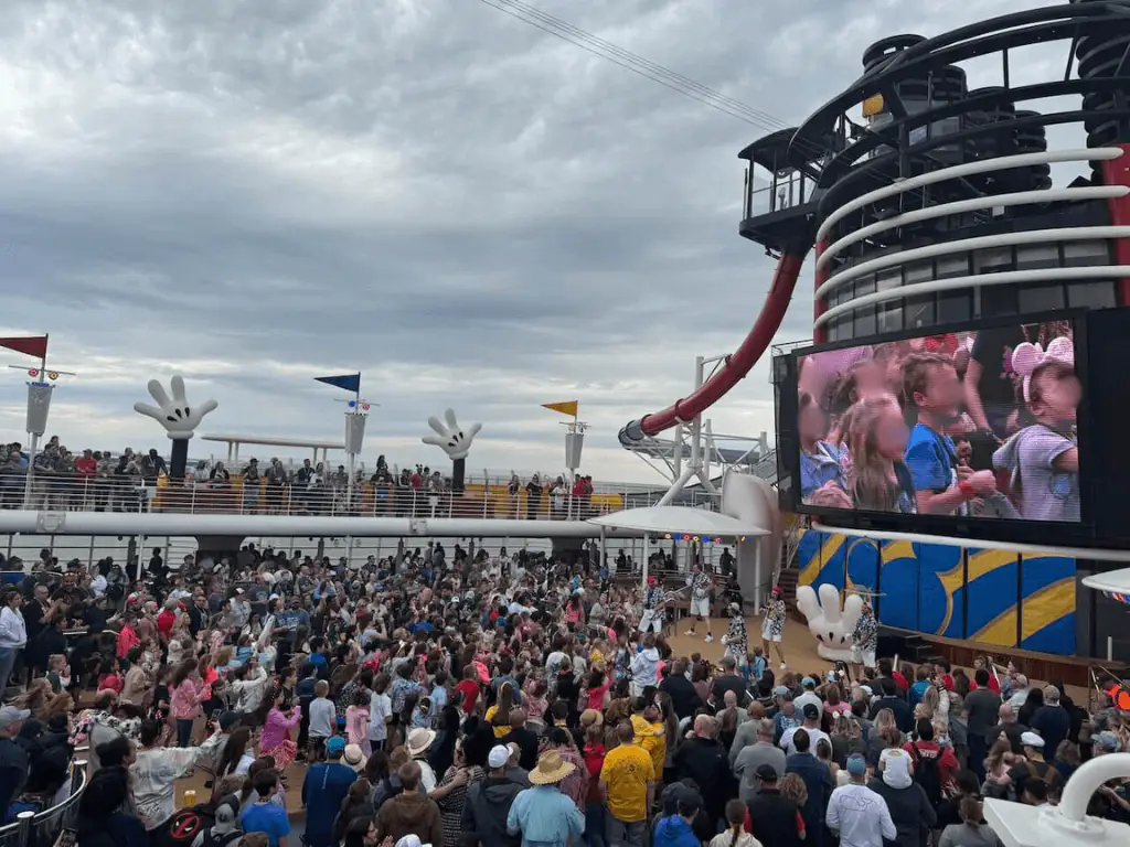People are standing up and getting ready for Disney Cruise Sail Away Celebration Party on the top of the deck.