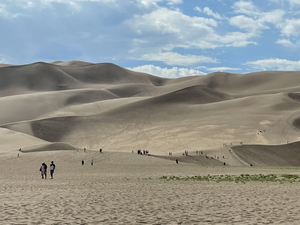 People that look small while walking up to the Great Sand Dunes national park in Colorado.