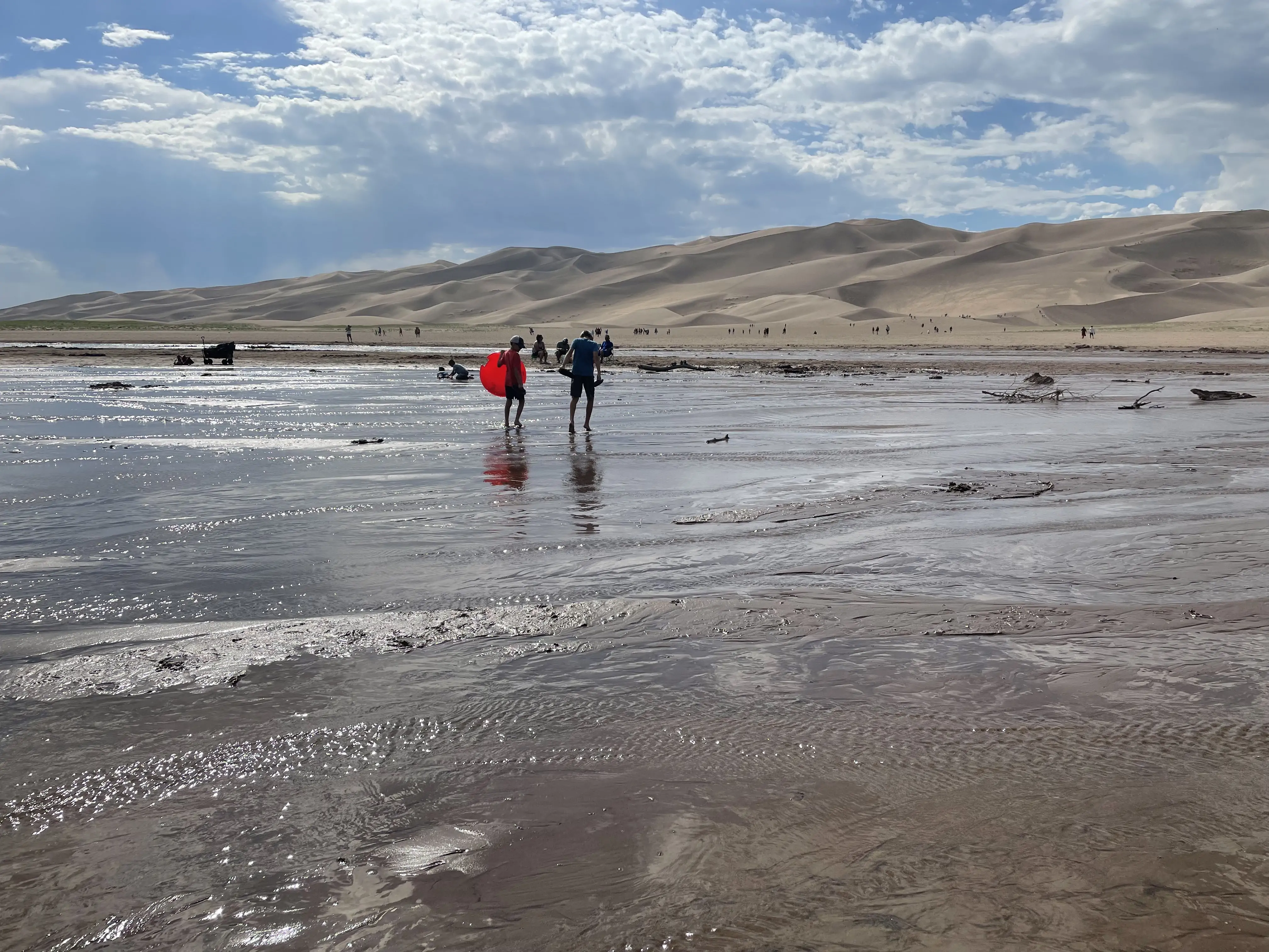 Two boys are crossing Medano Creek in Great Sand Dunes National Park.