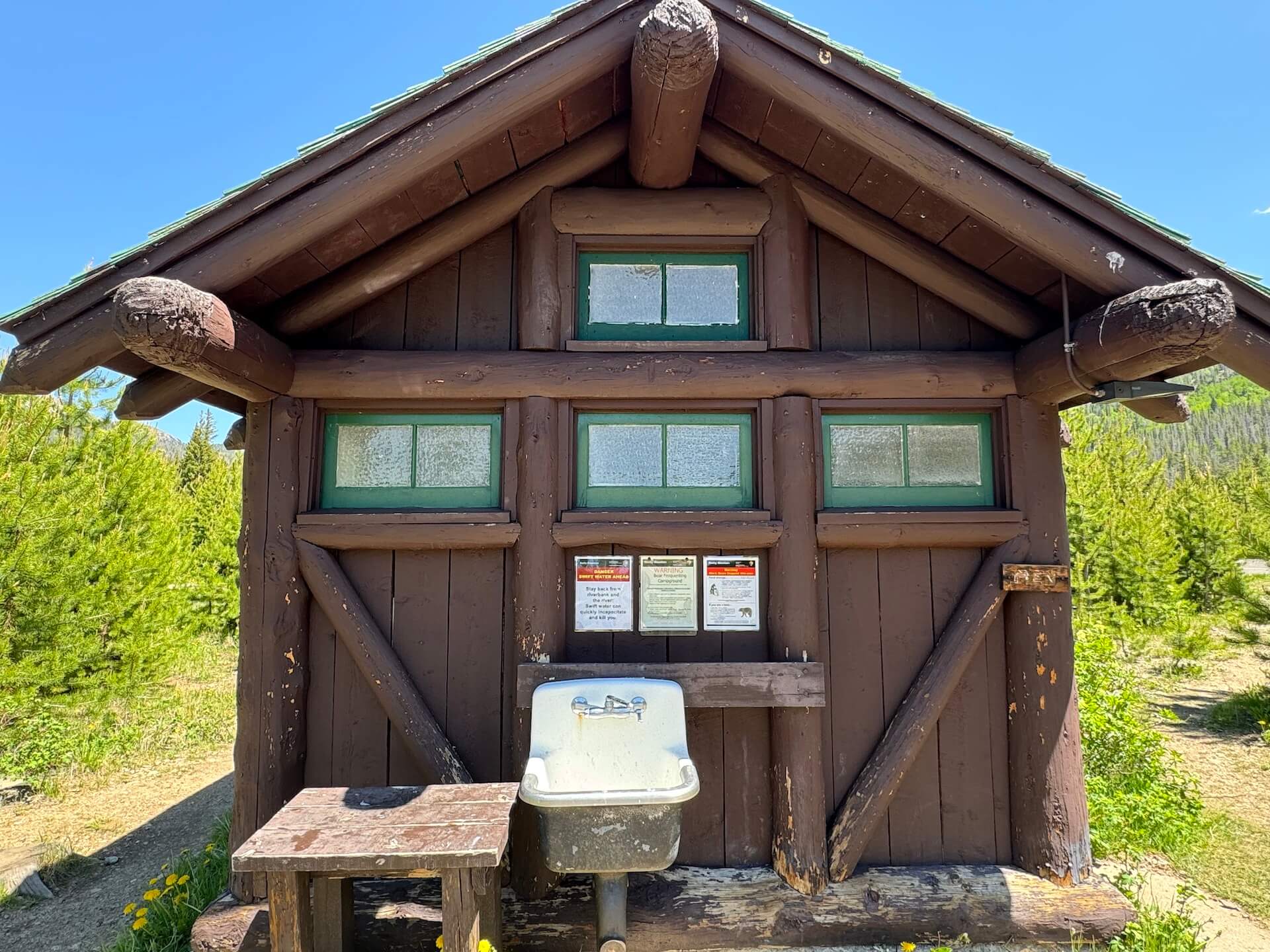 Wooden shed with an outdoor sink for washing dishes.