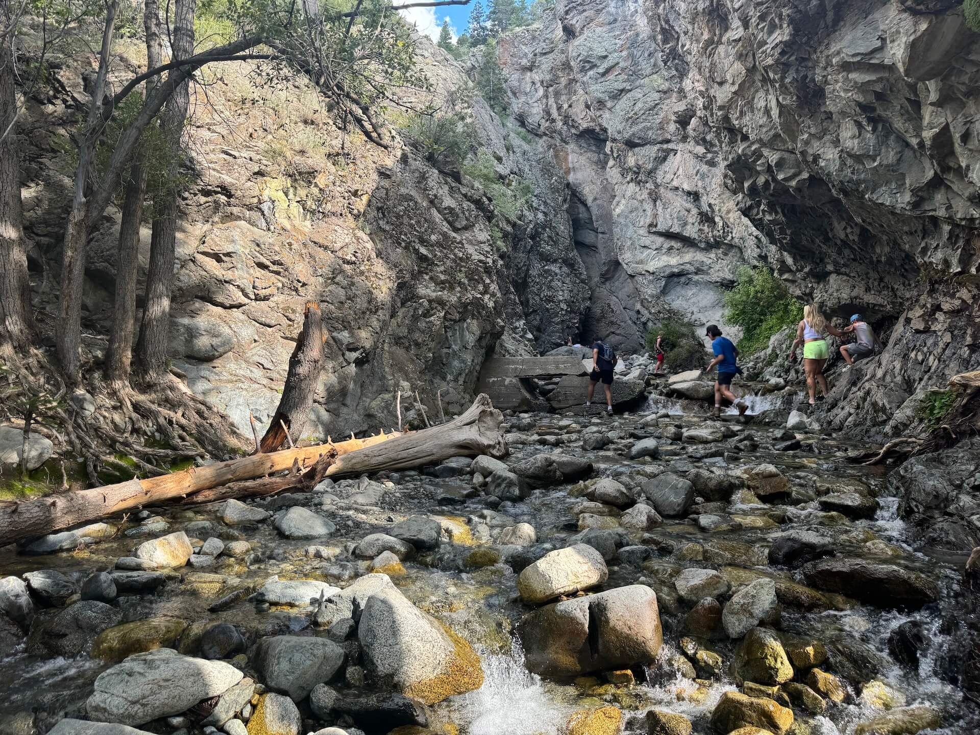 A young boy stands at the water's edge, gazing up at Zapata Falls.