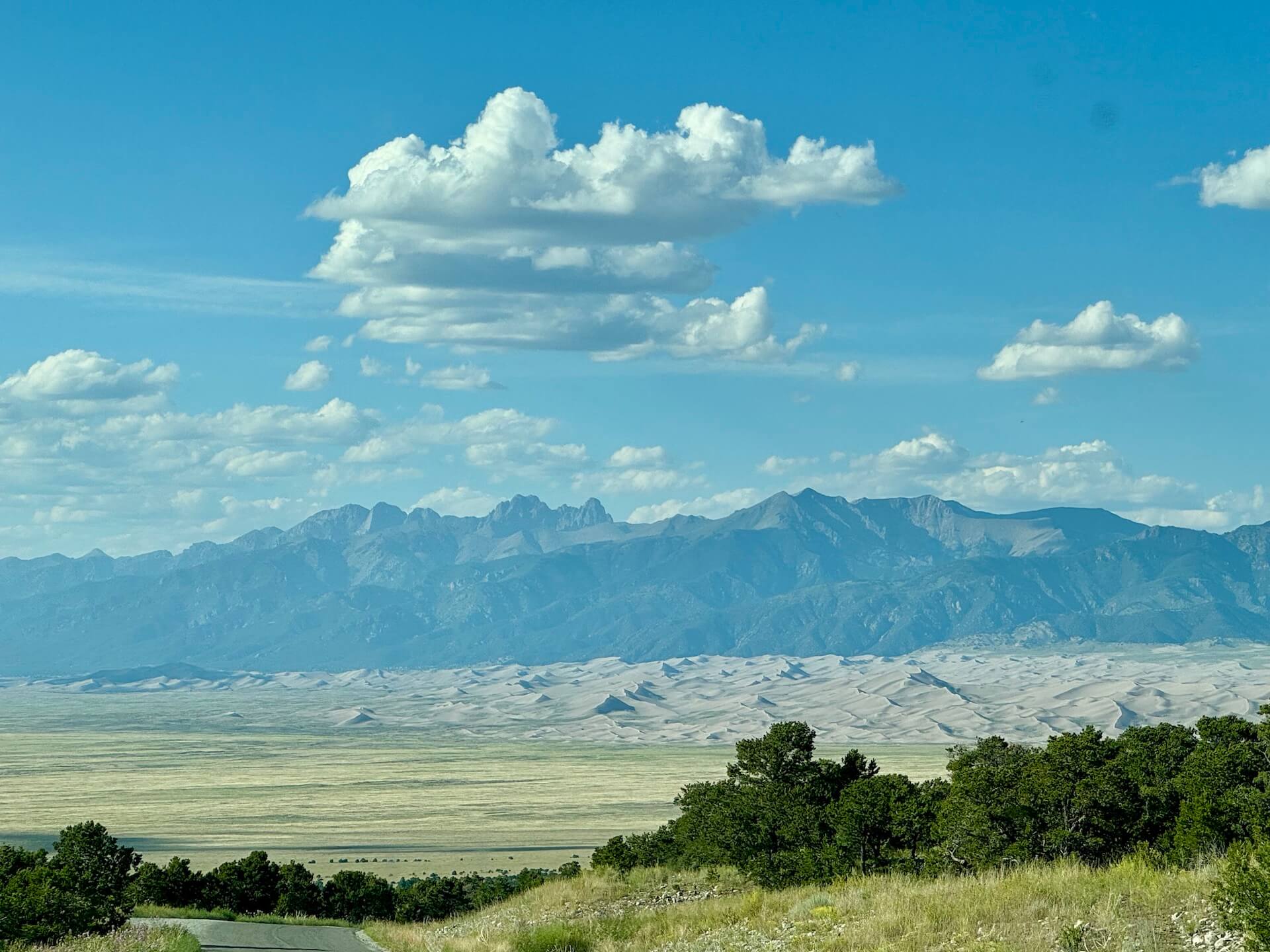 ZapataFalls_Road - Tomo Travel & Camping A downhill path with a view of the Great Sand Dunes stretching out on the road, Zapata Fall Road.