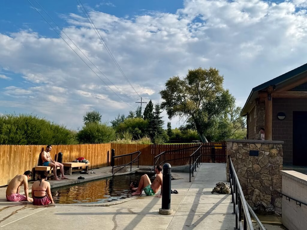 Adults relaxing in the oval-shaped hot spring at HoBO Hot Springs in Saratoga, Wyoming.