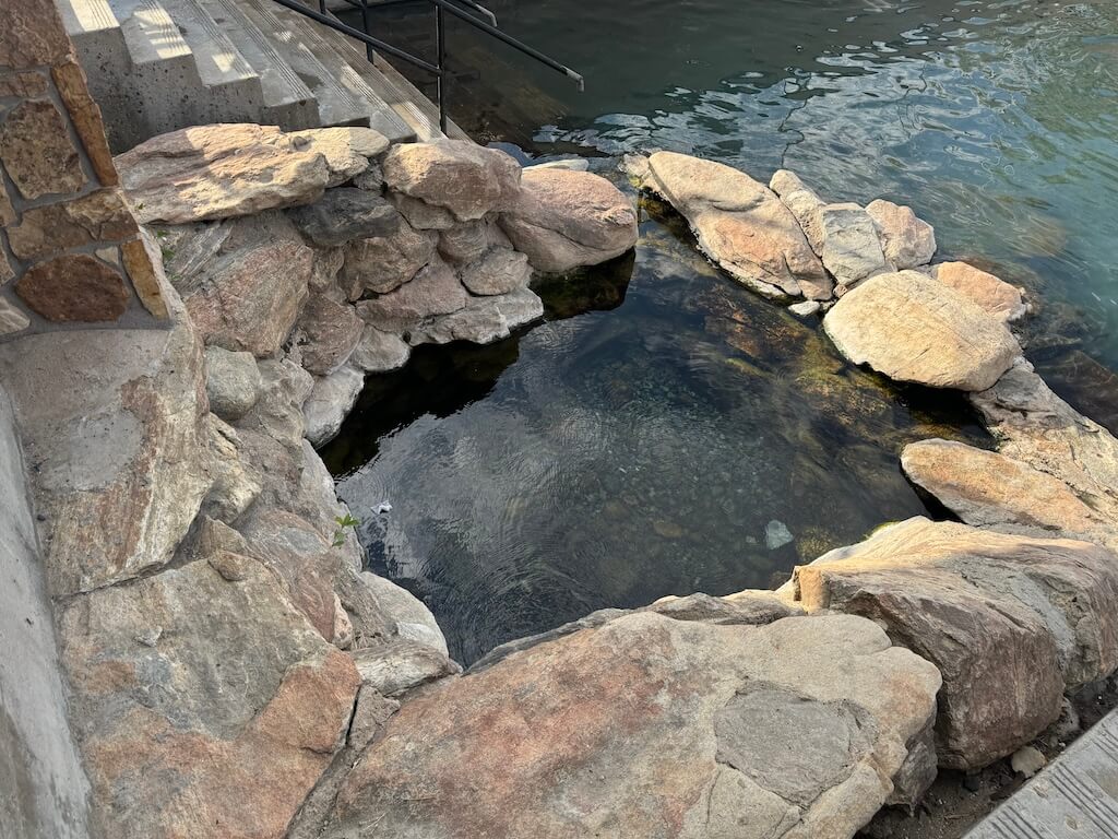 The smallest hot spring at HOBO Hot Springs in Saratoga, surrounded by rocks.