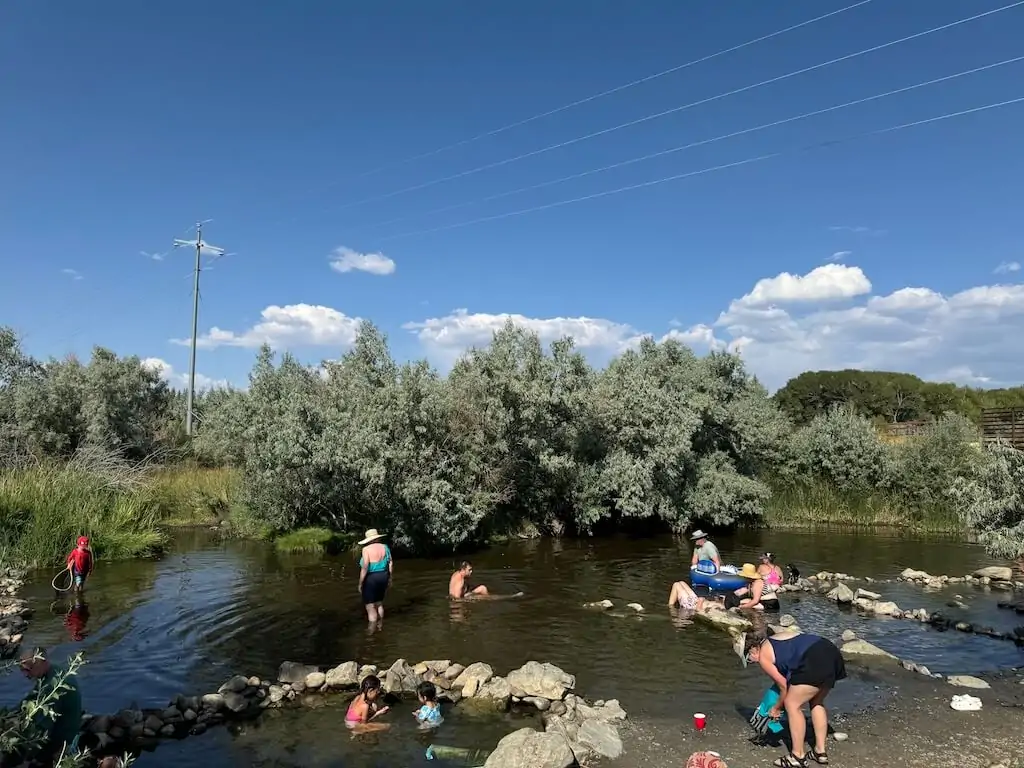 People relaxing in the warm North Platte River, where hot spring water flows from Hobo Hot Springs