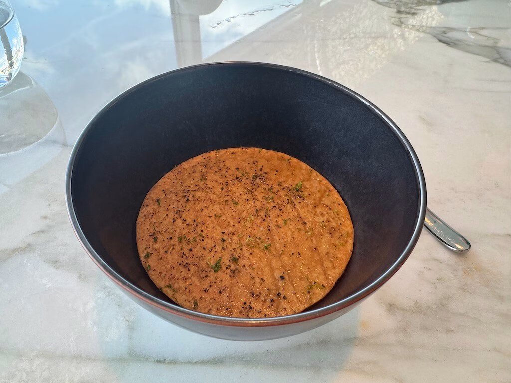 The orange-colored soup served as part of the course menu at Enchanté on the Disney Wish.