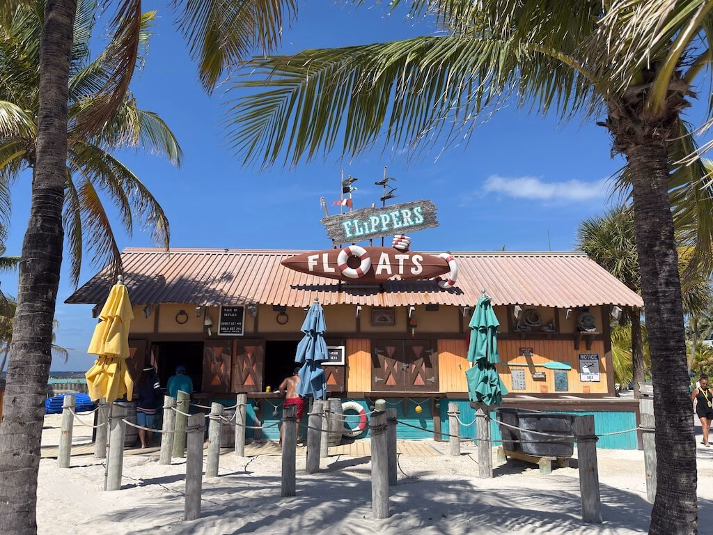 Brown building with sign of "Flippers Floats" surrounded by palm trees.