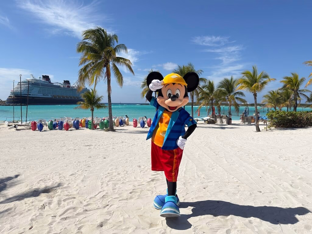 Mickey is leaning on the colorful jeep in the background of Disney Cruise at Castaway Cay.