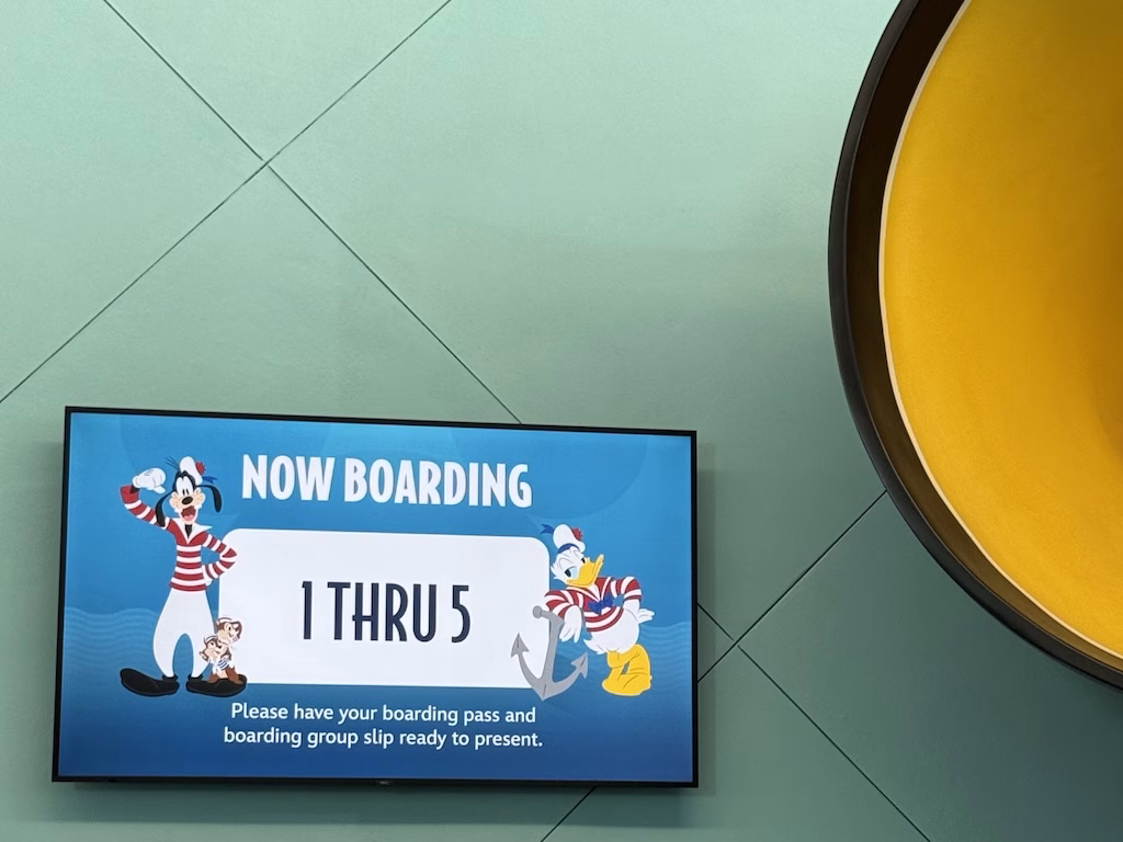 Disney Cruise Line terminal boarding screen showing groups 1 through 5 now boarding, with Goofy and Donald Duck in sailor outfits