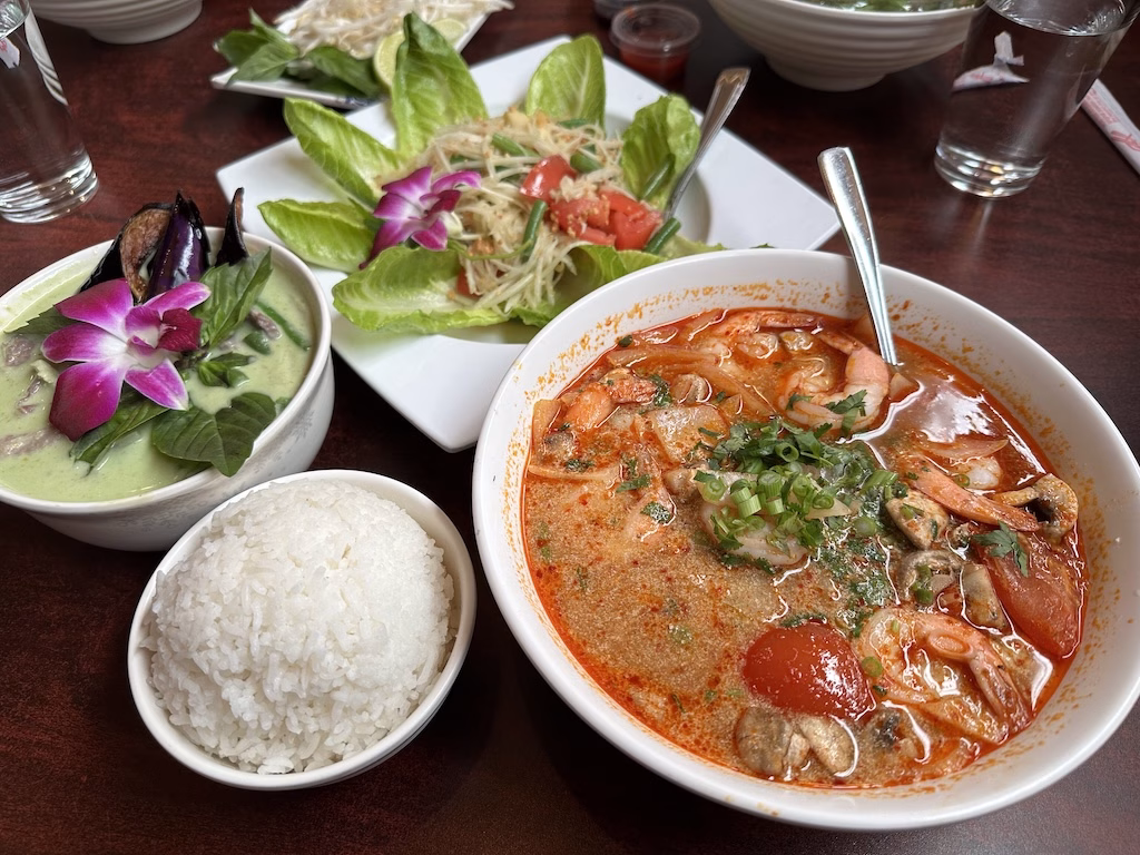 ユタ州モアブの人気タイ料理店「Arches Thai」で提供されるグリーンカレー、トムヤムスープ、パパイヤサラダ、ご飯のセット。色鮮やかでボリュームたっぷりの本格アジアンメニュー。