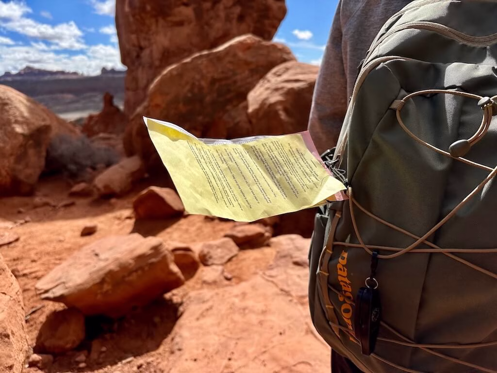 Close-up of a Fiery Furnace hiking permit attached to a backpack at Arches National Park, highlighting the importance of advance reservations for this unique Moab trail.