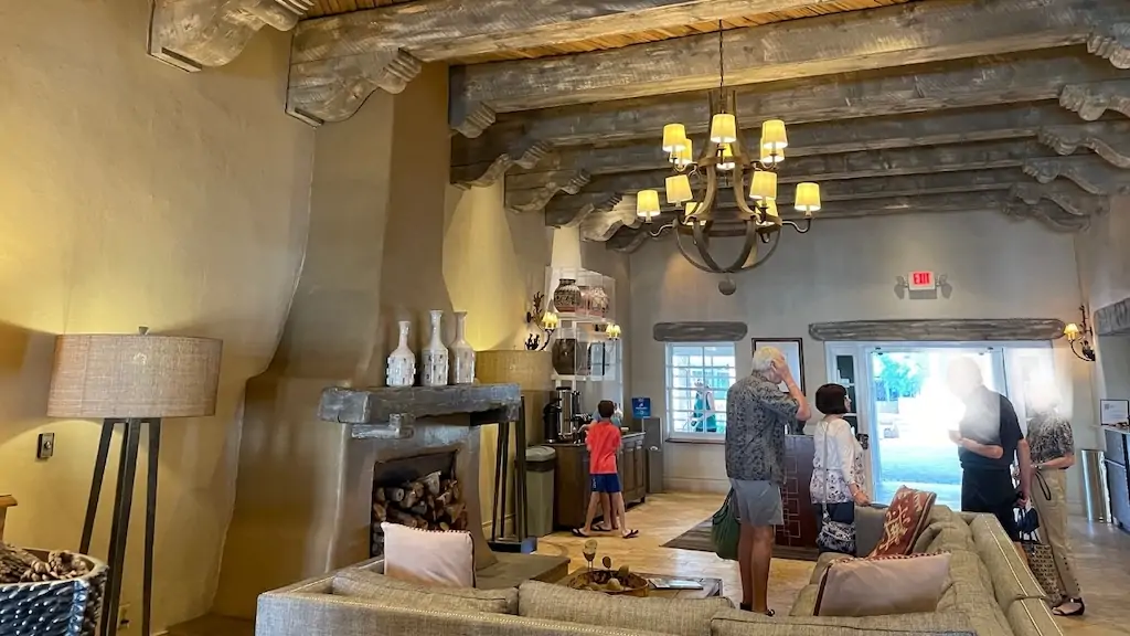 Lobby of Hilton Santa Fe with Southwestern-style wooden beams, cozy fireplace, and relaxed seating—perfect for travelers exploring Meow Wolf Santa Fe and top things to do in Santa Fe, New Mexico.