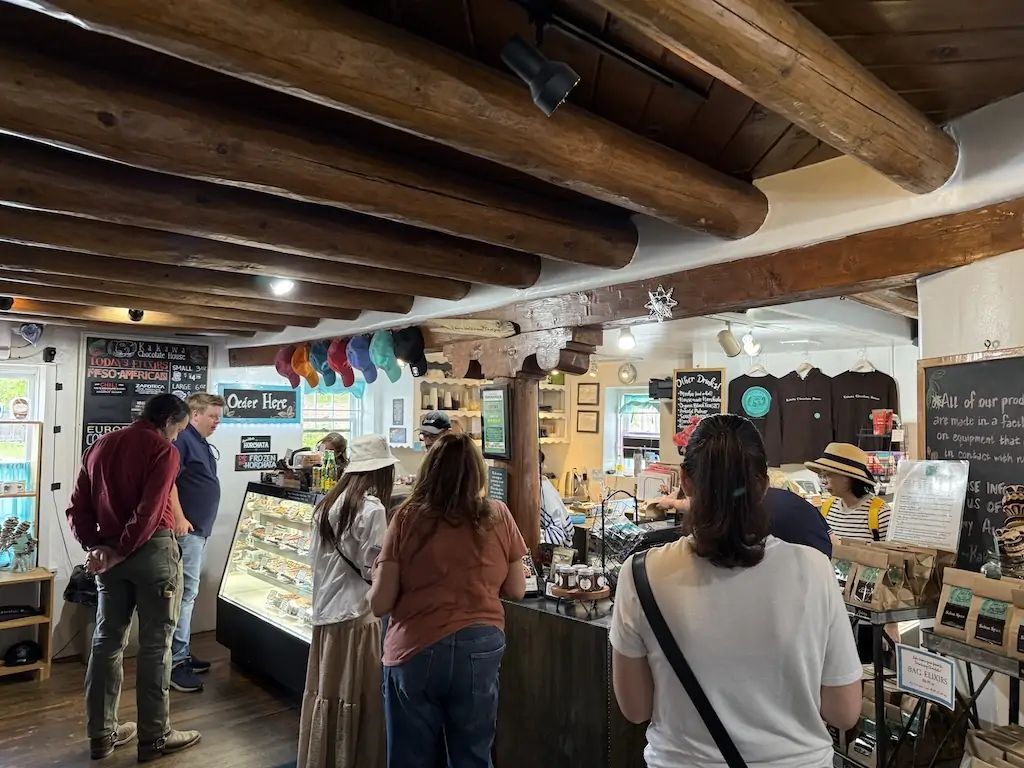 Visitors inside Kakawa Chocolate House in Santa Fe, New Mexico, enjoying handcrafted chocolates and elixirs in a cozy, rustic space—an essential stop when deciding where to go in Santa Fe for unique local flavors.