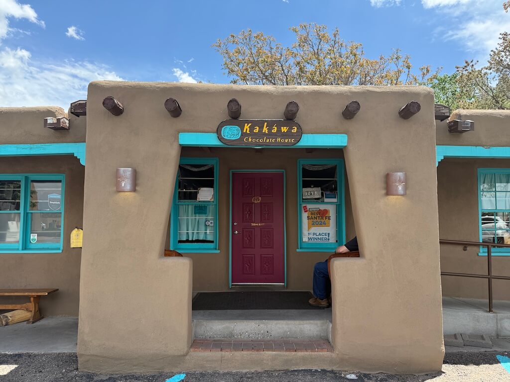 Kakawa Chocolate House Santa Fe – A Must-Visit Spot for Sweet Lovers Wondering Where to Go in Santa Fe - Tomo Travel & Camping ニューメキシコ州サンタフェにあるカカワ・チョコレート・ハウスの外観。アドビ建築にターコイズのアクセントが映える、地元の味を楽しめる人気スポット