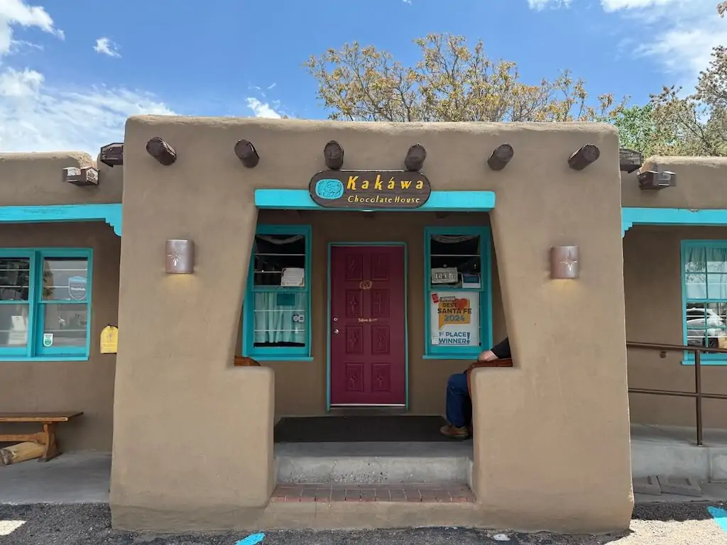 Exterior of Kakawa Chocolate House in Santa Fe, New Mexico, featuring adobe architecture with turquoise accents—one of the top-rated stops for visitors wondering where to go in Santa Fe for authentic local treats.