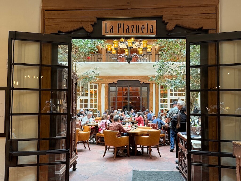 La Plazuela at La Fonda – Iconic Santa Fe Dining in a Historic Courtyard Setting - Tomo Travel & Camping ニューメキシコ州サンタフェにあるラ・フォンダ・オン・ザ・プラザの館内。スペイン風の伝統的な装飾、手作りの木製家具、宗教アートが特徴で、ミャオウルフや歴史地区観光にも便利な人気宿泊先
