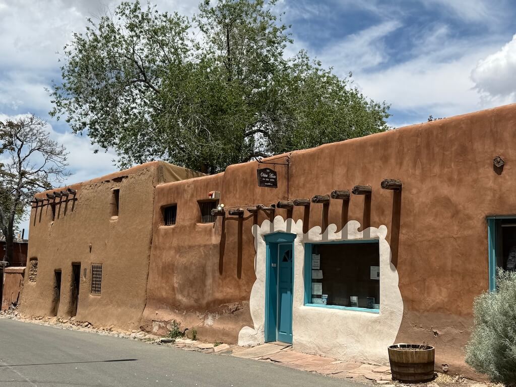 Oldest House in Santa Fe – Historic Adobe Landmark in Downtown Santa Fe, New Mexico - Tomo Travel & Camping ニューメキシコ州サンタフェにあるアメリカ最古の家。保存されたアドビ壁とターコイズの扉が特徴の南西部らしい伝統的建築で、周辺には他の歴史的スポットも点在