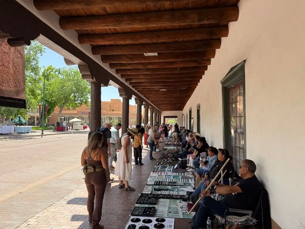 Native artists selling handcrafted jewelry under the covered walkway of the historic Santa Fe Plaza—an essential cultural stop when deciding where to go in Santa Fe for authentic local experiences.