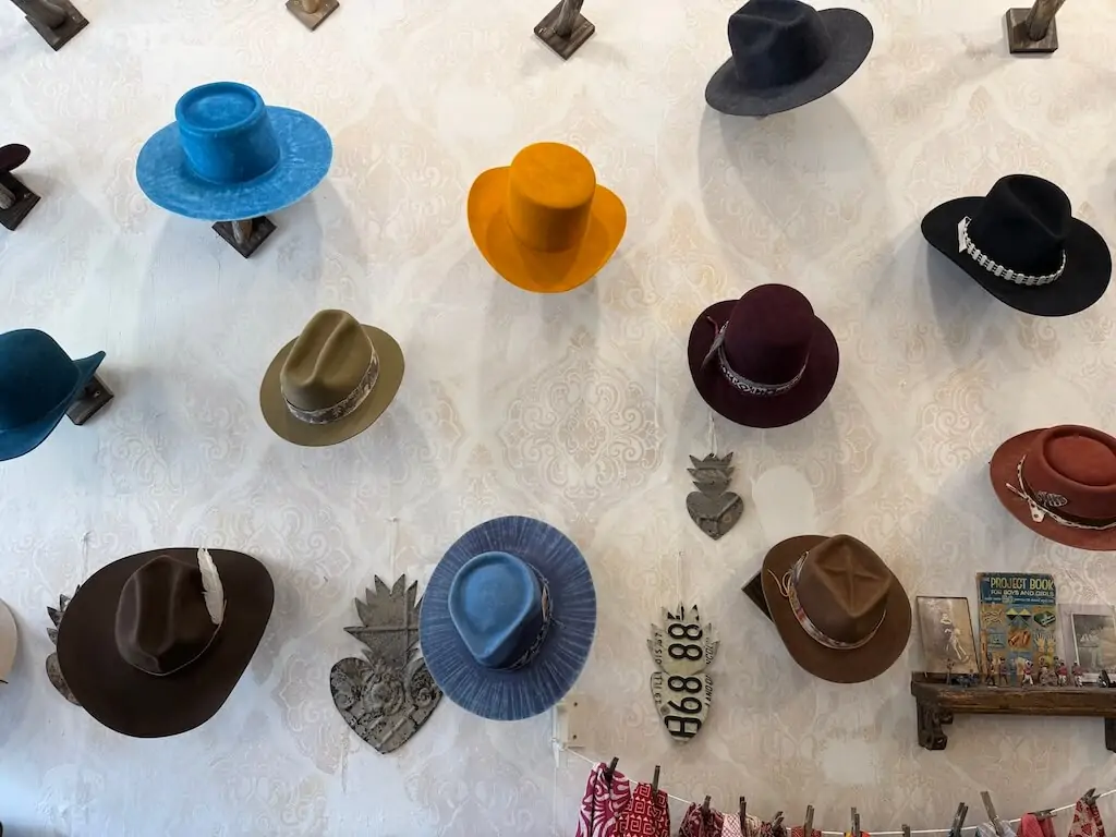 Wall display of handmade hats in vibrant colors at Six Hand Hat Co., a local artisan shop in Taos, New Mexico.