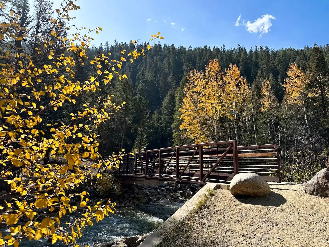 Bridge over Geneva Creek surrounded by golden aspen trees at Guanella Pass, a top destination for fall foliage in Colorado.