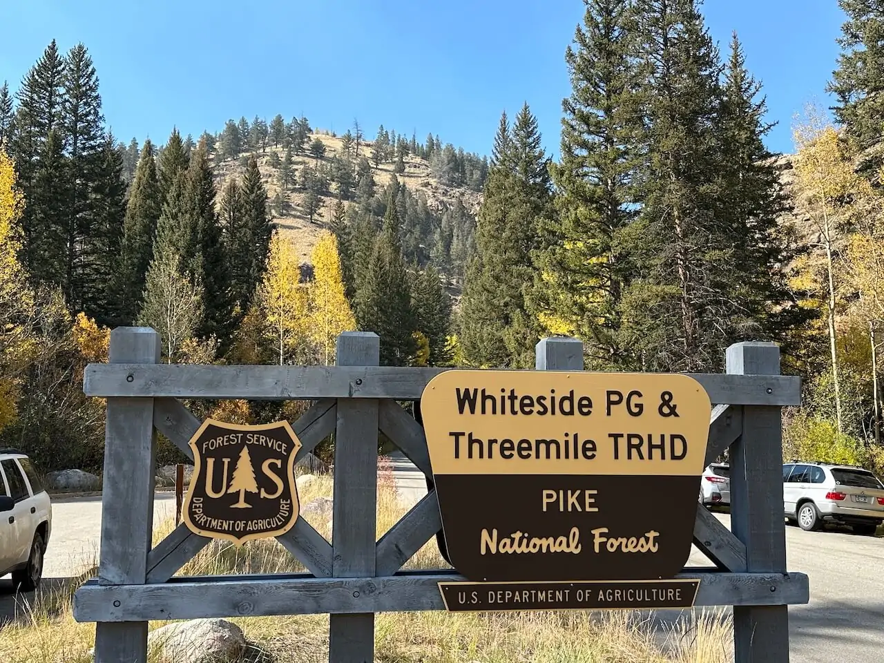 Sign for Three Mile Trailhead at Guanella Pass in Pike National Forest, surrounded by fall colors in Colorado.