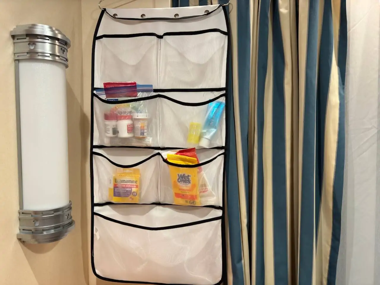 Hanging pocket organizer in a Disney Cruise stateroom storing sunscreen, medicine, wipes, and toiletries for easy cabin organization
