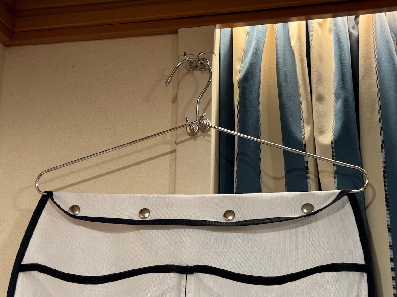 Disney Cruise Cabin Organization Hack: How to Hang a Pocket Organizer in Your Stateroom - Tomo Travel & Camping ディズニークルーズの客室でマグネットフックを使ってポケットオーガナイザーを吊り下げている様子。限られた船室スペースを有効活用する収納アイデア。