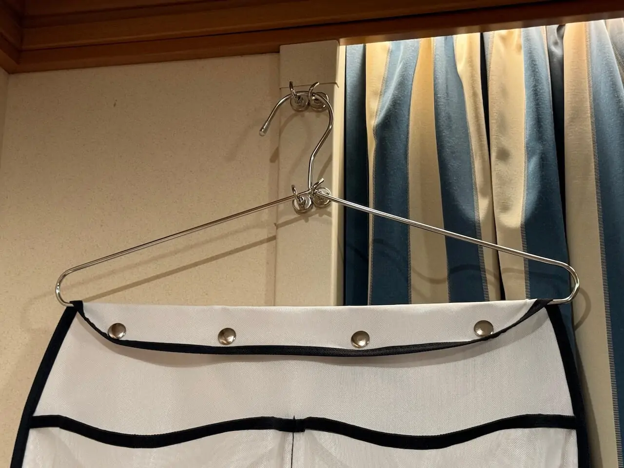 Close-up of a pocket organizer hung on a metal hanger and hook inside a Disney Cruise stateroom for extra storage space.