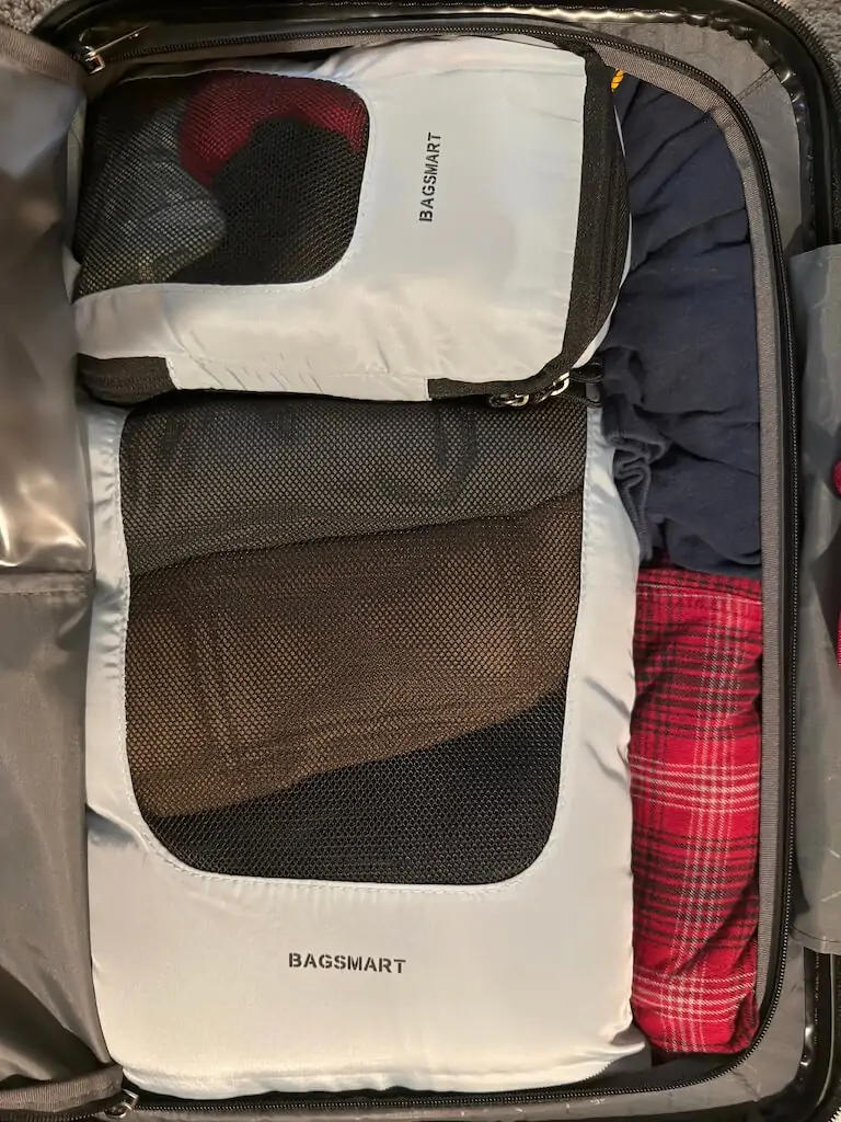 Suitcase packed with Bagsmart blue and gray packing cubes to organize clothing for a Disney Cruise vacation