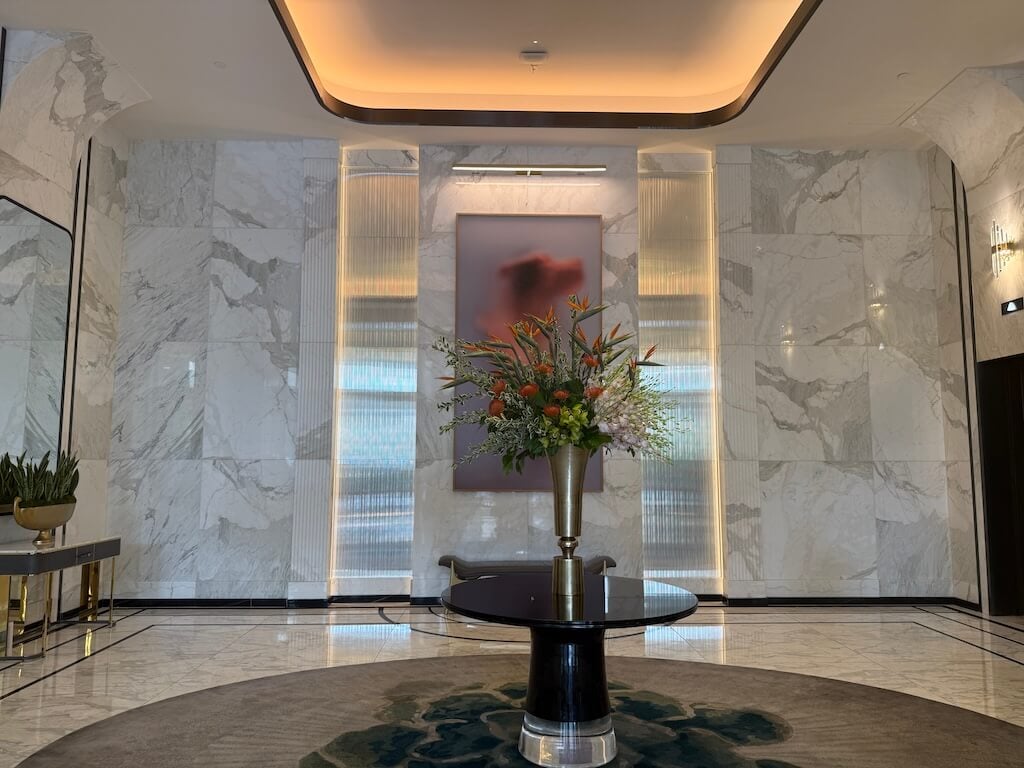 Waldorf Astoria Las Vegas Lobby Interior – Elegant Hotel Entrance - Tomo Travel & Camping ウォルドルフ・アストリア・ラスベガスのエレガントな大理石ロビー。モダンなフラワーアレンジメントと高級感あふれるインテリアデザインが特徴。