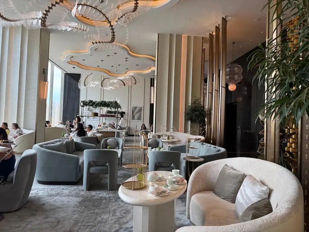 ウォルドルフ・アストリア・ラスベガスのエレガントな「ピーコック・アレー」ラウンジ。快適なソファ席とラスベガスの街並みを望む空間で、三段トレーのアフタヌーンティーを提供。