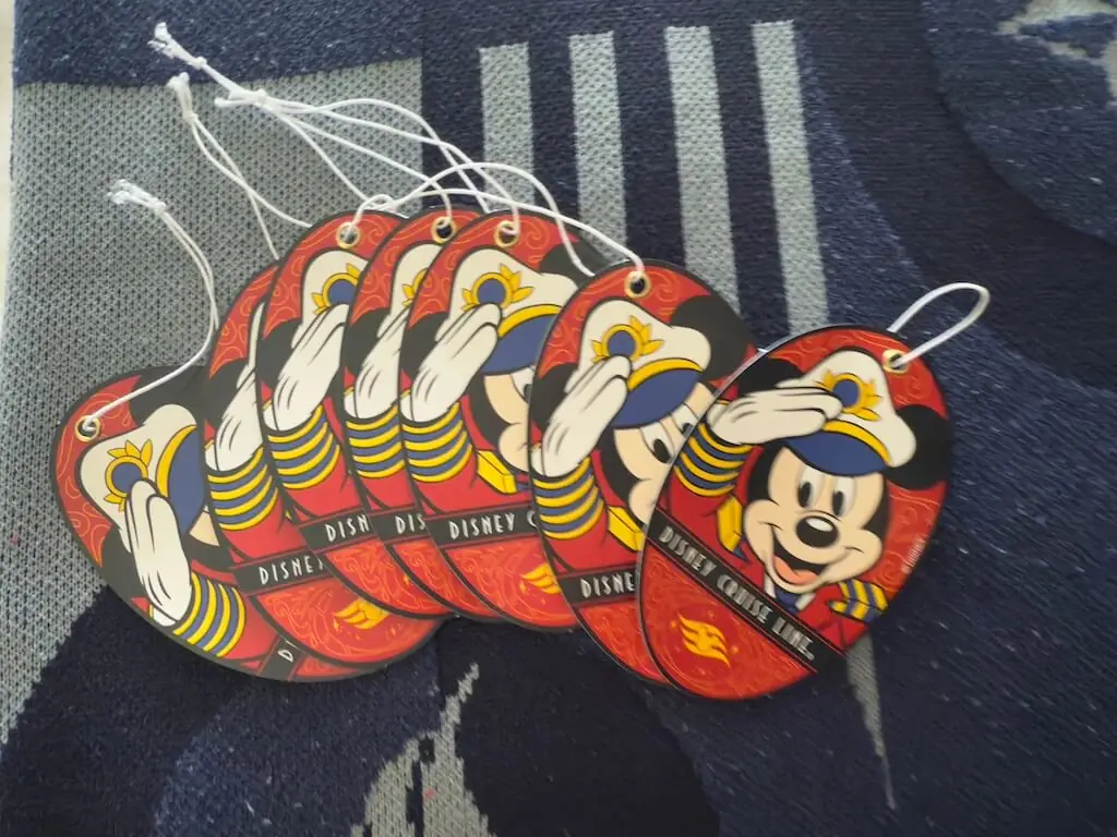 ディズニークルーズのベッドに並べられた紙のミッキー船長の荷物タグ