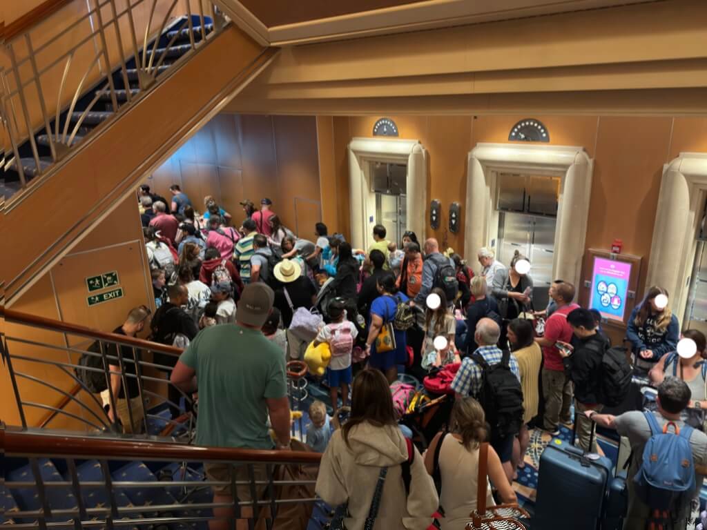 Crowded elevator area on Disney Cruise ship during disembarkation morning with guests waiting to exit