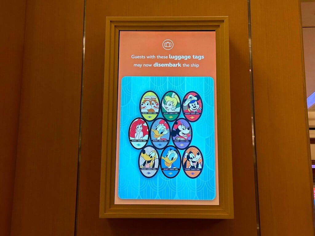 Digital screen showing Disney Cruise luggage tag character groups cleared to disembark